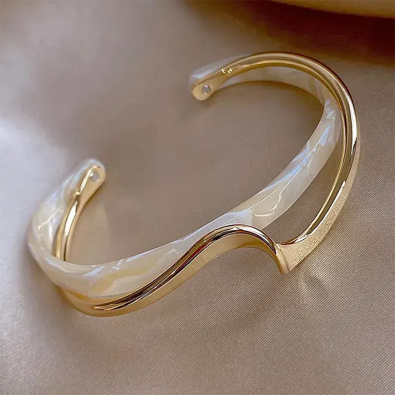 Elegant open bracelet crafted from white enamel and gold.