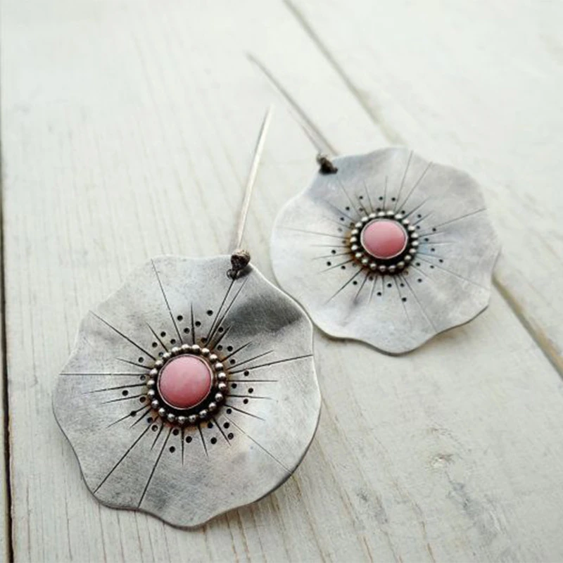 Vintage earrings featuring silver petals and a red gemstone.